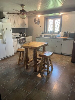 A kitchen with white cabinets, a wooden table, and stools. - Cozy House, Sleeps 14 and 12 miles to the visitor center in Benezette, PA (Weedville)