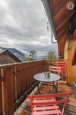 Enjoy breathtaking views of the surrounding mountains from this balcony with a table and two chairs.