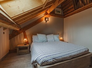 Cozy attic bedroom with a large bed, bedside tables, and a framed picture.