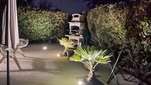 Eine Terrasse mit einem weißen Stuhl, einem kleinen Tisch und zwei Blumentöpfen.