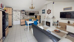 Eine moderne Küche mit Essbereich, Kamin und Fernseher.