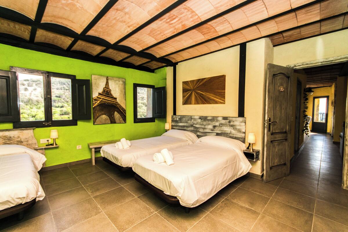 A hotel room with two beds, green walls, and artwork including a picture of a temple.
