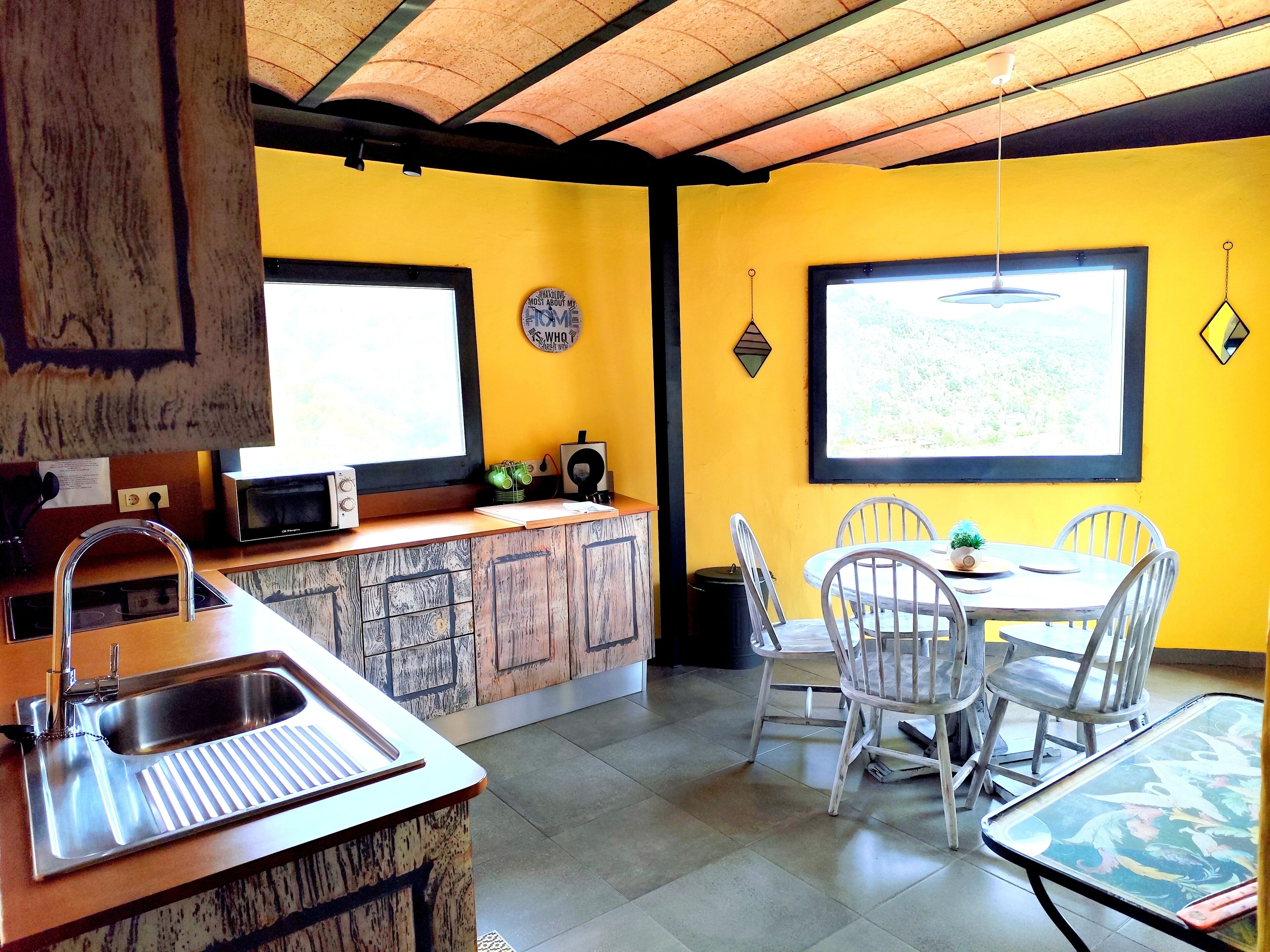 A kitchen with a sink, stove, and dining area with chairs and a table.