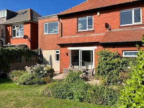 A two-story brick house with a patio area, a sliding glass door, and a satellite dish. - Sea View 5* Property, Sleeps 10, Parking, Dogs (Whitby)