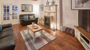A living room with a fireplace, sofa, coffee table, and a television.