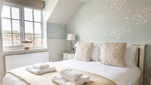 Ein Schlafzimmer mit Bett, Handtüchern, einem Nachttisch, einer Lampe und einem Fenster mit Blick.