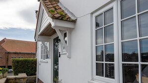 Ein weißes Gebäude mit einem Ziegeldach, einem großen Fenster und einer Tür.