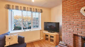 A living room with a large window, a flat-screen TV, a fireplace, and a sofa. - Elevated Dog friendly Cottage with Stunning Views (Whitby)