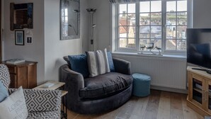A living room with a sofa, a television, a window with a view, and a lamp. - Elevated Dog friendly Cottage with Stunning Views (Whitby)