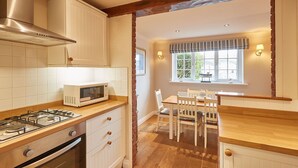 A compact kitchen with a gas stove, microwave, and white cabinetry. - Elevated Dog friendly Cottage with Stunning Views (Whitby)