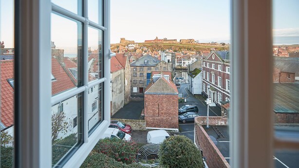 A view of a town with historic buildings, a prominent tower, and a clear sky. - Elevated Dog friendly Cottage with Stunning Views (Whitby)