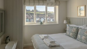 A bedroom with a bed, a window with a view, a bedside table, and a lamp.