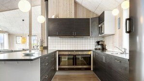 Una cocina moderna con alacenas de madera oscura, una isla central y hornos empotrados.
