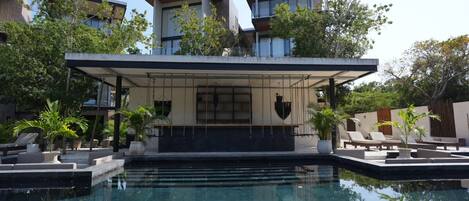 Una piscina al aire libre, sombrillas, sillones reclinables de piscina