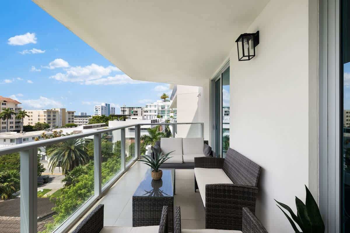 A balcony with a sofa, a table, and a potted plant.