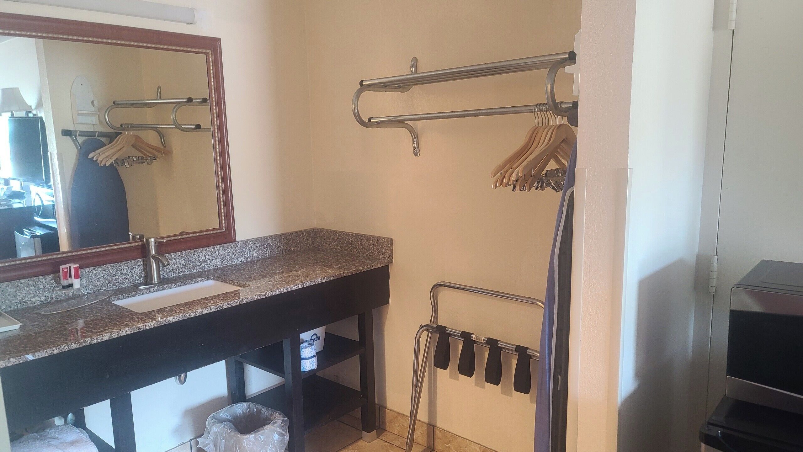 A bathroom with a granite countertop sink, a mirror, a towel rack, and a shower area.
