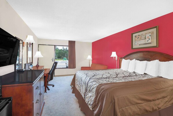 A hotel room with a bed, desk, chair, and a television.