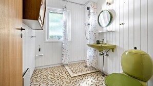 A bathroom with a green toilet, a sink with a mirror, a shower with a curtain, and a window with a view of greenery. - 3 bedroom lovely home in Høng (Høng)