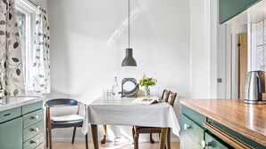 A dining area with a table set for two, a pendant light, a vase with flowers, and a kettle on the counter. - 3 bedroom lovely home in Høng (Høng)