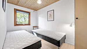 A bedroom with two beds, a window with a view of trees, a framed picture on the wall, and a bedside lamp. - 3 bedroom lovely home in Høng (Høng)