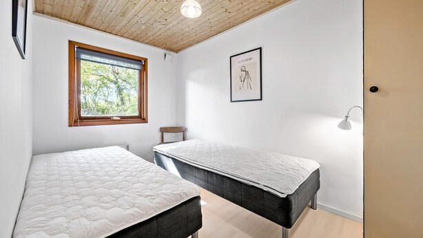 A bedroom with two beds, a window with a view of trees, a framed picture on the wall, and a bedside lamp. - 3 bedroom lovely home in Høng (Høng)