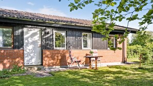 A house with a brick exterior, a wooden door, and a window. There is a small table and a chair outside. - 3 bedroom lovely home in Høng (Høng)