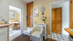 A cozy kitchen with wooden cabinets, a dining area with a table and chairs, and a hallway leading to a door. - 4 bedroom accommodation in Stamford (Stamford)
