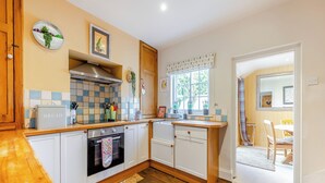 A kitchen with white cabinets, a wooden countertop, a built-in oven, and a window with a view of greenery outside. - 4 bedroom accommodation in Stamford (Stamford)