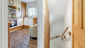 A kitchen with a wooden bench, a window with a view, and a brick wall. - 4 bedroom accommodation in Stamford (Stamford)