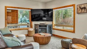 A cozy living room with a fireplace, large windows, and a television. - Cozy Chinook Cabin (Naches)