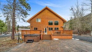 A wooden cabin with a central staircase, a hot tub, and a fenced deck area. - Cozy Chinook Cabin (Naches)