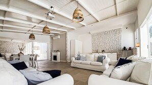 A spacious living area with a white sofa set, a fireplace, and a stone wall.