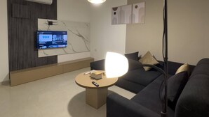 Ein modernes Wohnzimmer mit einer Couch, einem Couchtisch, einem Fernseher und einer Decken-Klimaanlage.