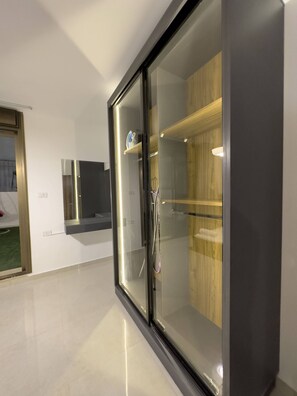 A modern room with a glass partition, a wooden cabinet, and a built-in TV.