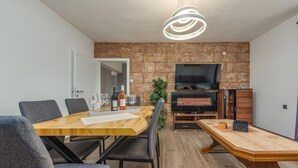Zona pranzo moderna con tavolo e sedie in legno, una televisione e una pianta.