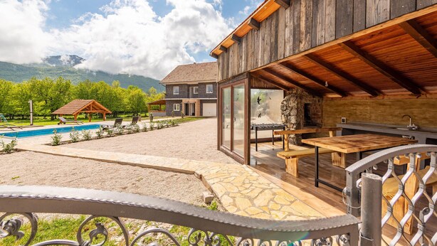 Una casa moderna con piscina, area salotto esterna e patio in pietra.