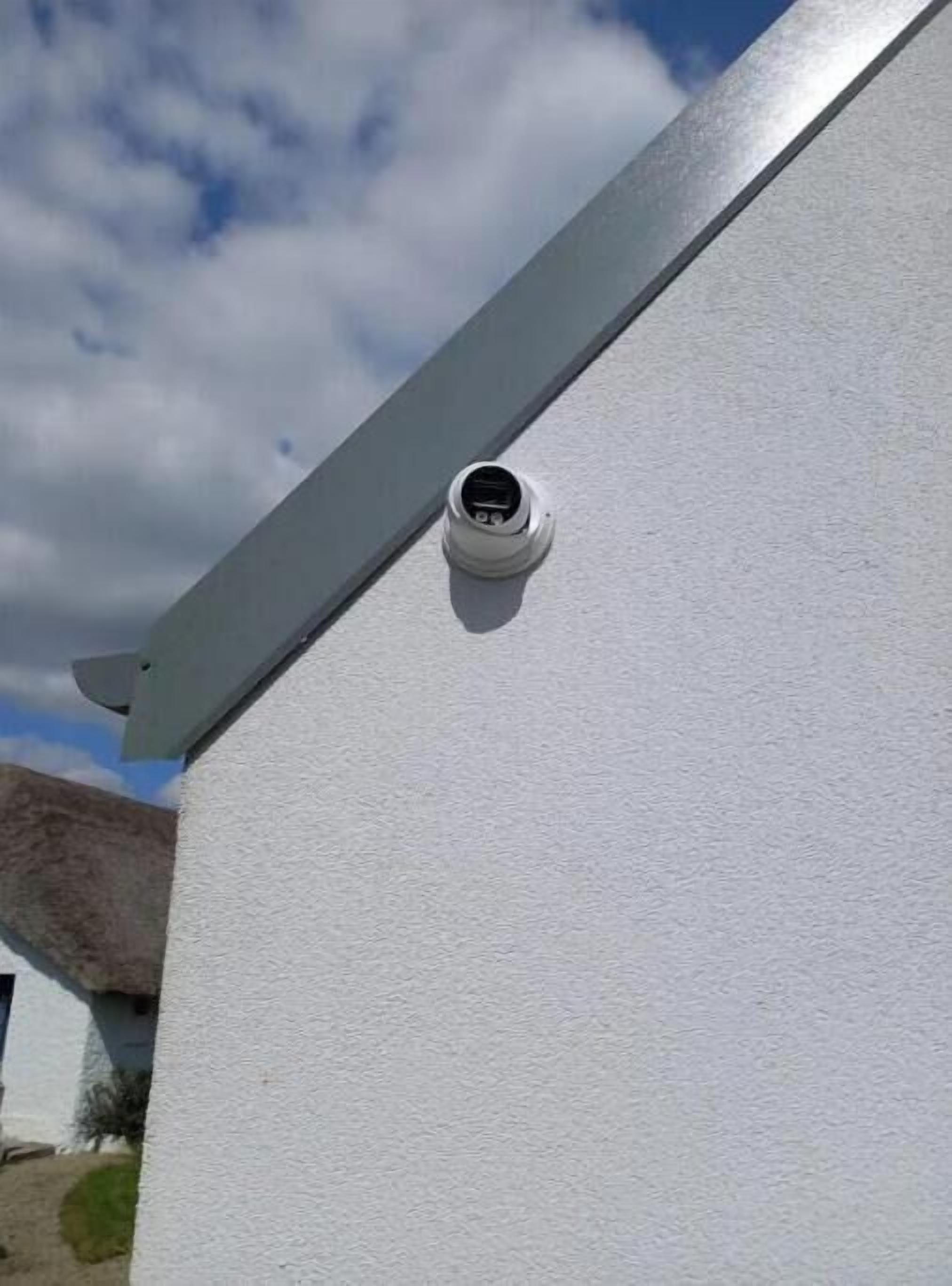 Ein weißes Gebäude mit einer an der Außenwand angebrachten Überwachungskamera.