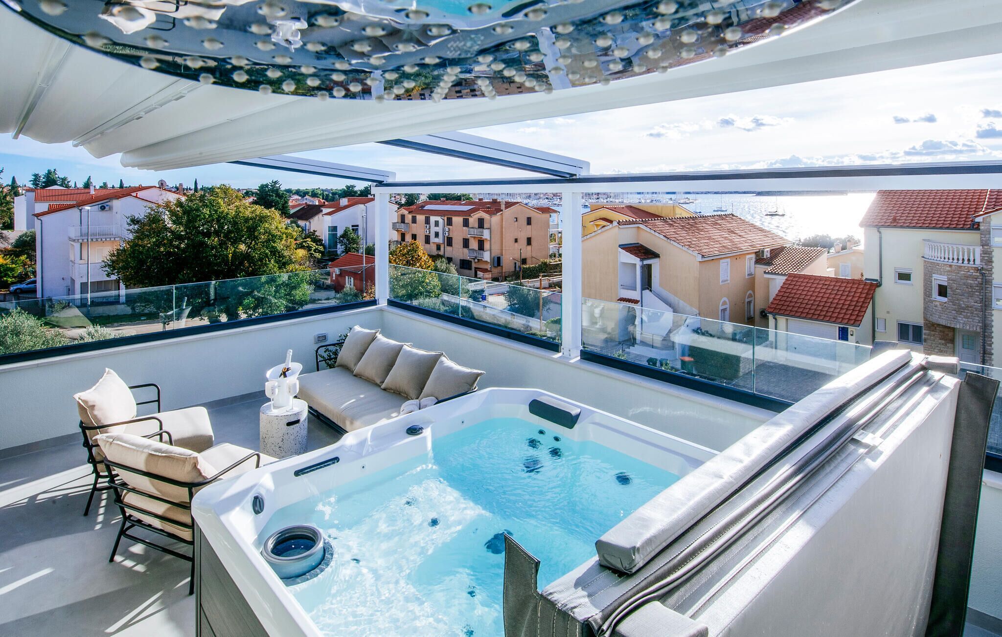 En takterrass med ett bubbelbad, utomhusmöbler och utsikt över stadsbilden.