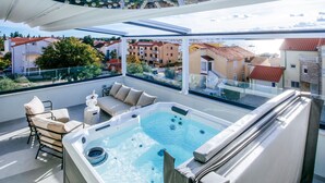 Une terrasse sur le toit avec un jacuzzi, des sièges extérieurs et une vue sur le paysage urbain.