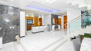 Una cocina moderna con encimeras de mármol, una zona de bar y una escalera que sube a un nivel superior.