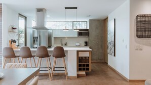 Una cocina moderna con una isla central, electrodomésticos de acero inoxidable y un amplio ventanal que proporciona luz natural.