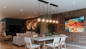 Un moderno comedor con pared de ladrillo, un cuadro abstracto grande y una mesa de comedor con sillas.