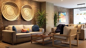 Una sala de estar moderna con una pared de ladrillo, dos piezas de arte mural tejidas, un sofá, una mesa de centro y una silla.