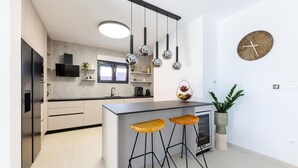 A modern kitchen with a central island, bar stools, pendant lights, a built-in oven, and a wall-mounted clock. - Awesome home in Kastel Stari with sauna (Kastel Stari)