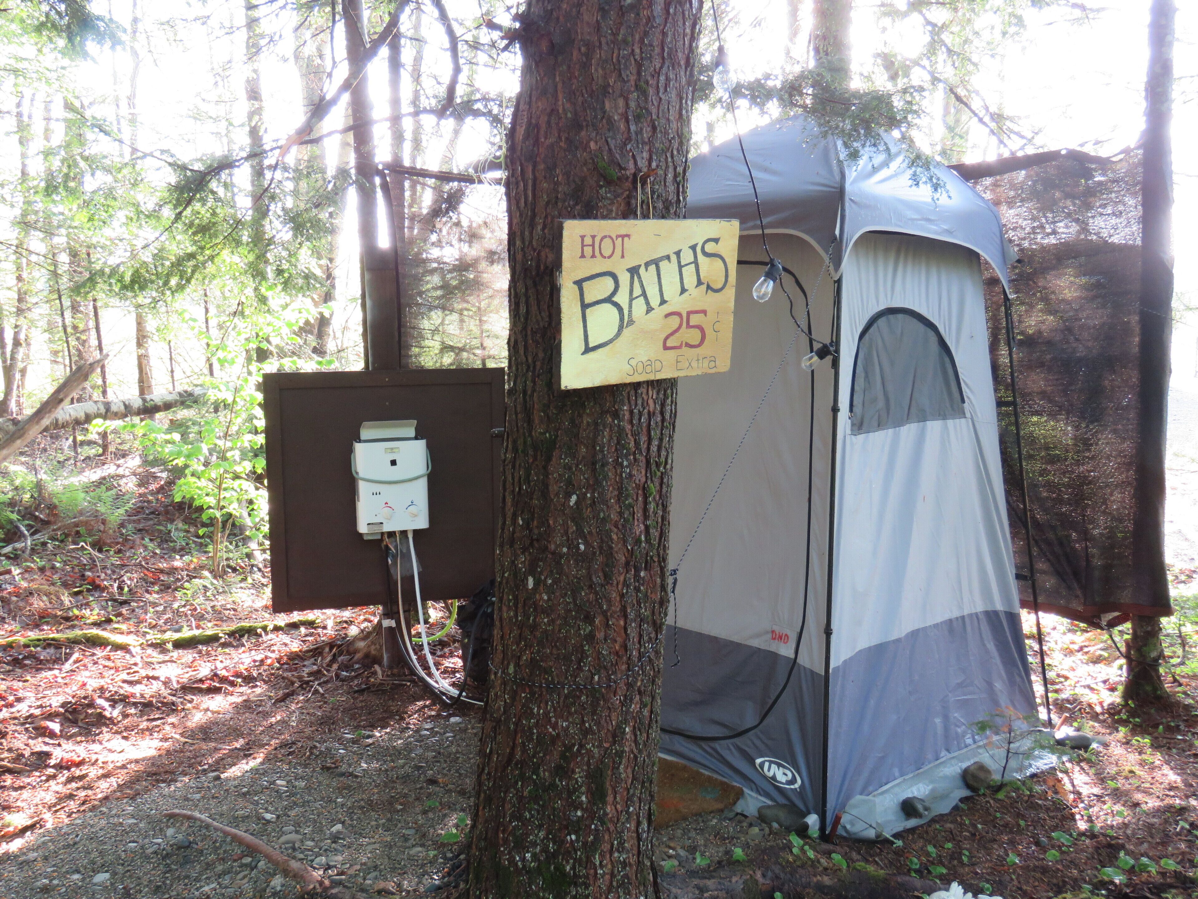 A portable toilet with a sign indicating it is a 'HOT BATHS' and has a temperature of 25°C.