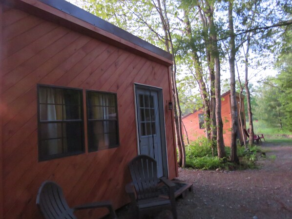 A rustic cabin with a wooden exterior, a front door, and two windows. - Schlafmans Hollow Solar Cabins (Lincoln)