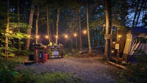 Un camping con una tienda de campaña, una mesa pequeña con botellas y un letrero que dice 'Baths 25'.