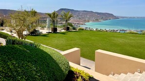 Un césped bien cuidado con vista al mar y montañas al fondo.