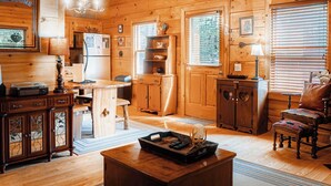 Un intérieur de chalet chaleureux avec des murs en bois, un coin repas, une cuisine et un espace détente doté d’une cheminée.