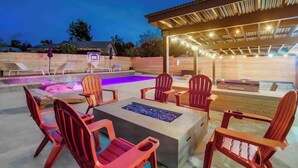 Un espace extérieur aménagé en terrasse, avec des fauteuils Adirondack rouges, un foyer et une piscine.